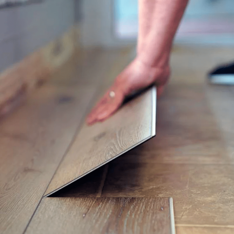 Ambiente moderno con piso vinílico SPC imitación madera instalado en sala de estar, ideal para hogares por su resistencia al agua y fácil mantenimiento.